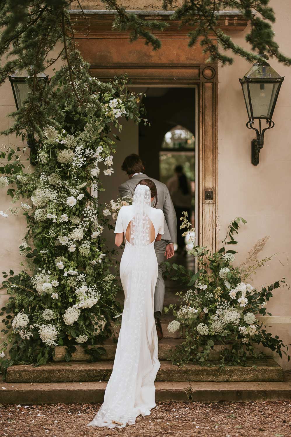 Bride and groom entering Aswarby Rectory with doorway surrounded by flowers. Photo ©Rosie Kelly Photography