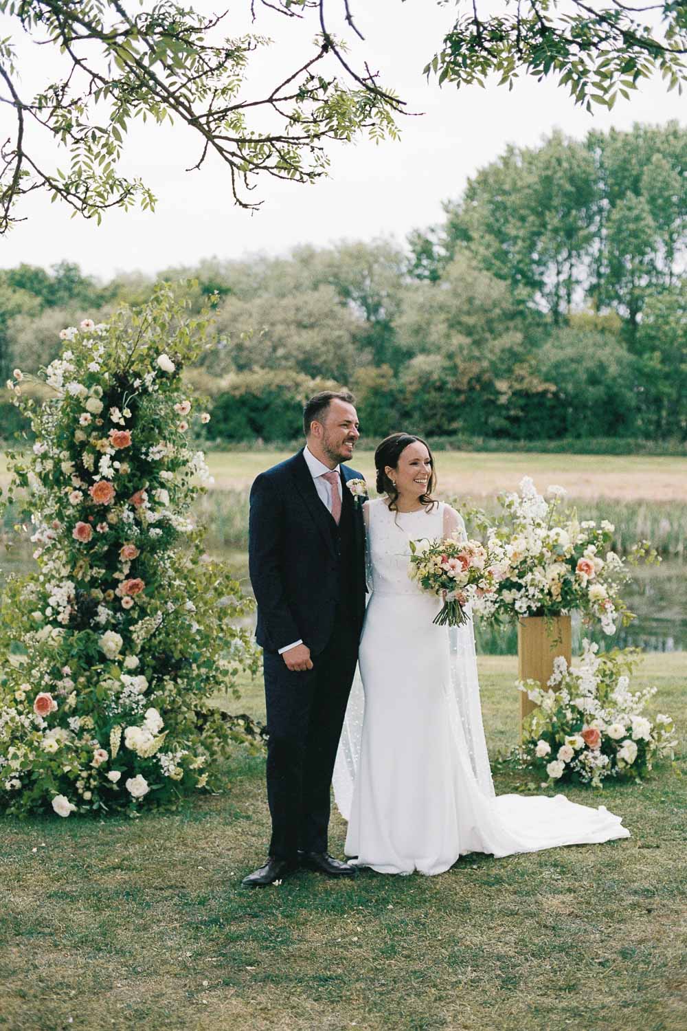 Outdoor ceremony with bride and groom surrounded by flooral arrangements at Willow Marsh Farm. Photo ©Daisy Price Photography